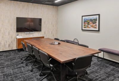 Professional meeting room featuring a large wood conference table and abstract artwork.