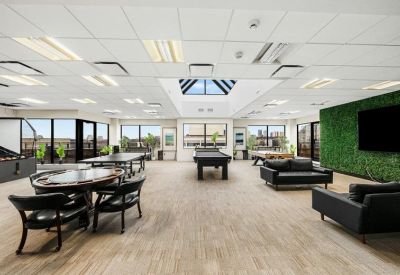 Spacious recreation room with a pool table, lounge area, and a green plant feature wall.
