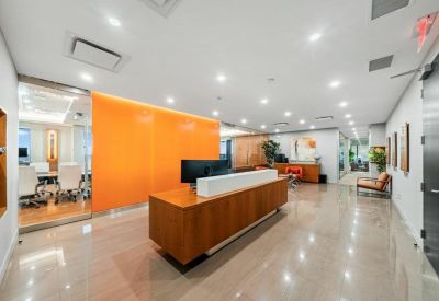 Professional reception area with a wood-front desk and a bright orange feature wall.
