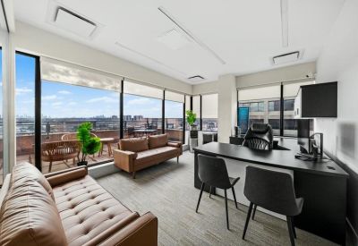 Private office featuring brown leather sofas and floor-to-ceiling windows with city views.