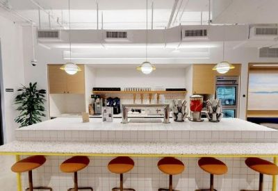 Kitchenette area featuring a white tiled island with bar stools and coffee machines.