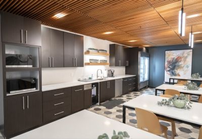 Modern kitchenette and breakroom with dark cabinets and cafe-style seating.