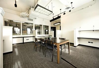Spacious open-plan office area with large communal table and bright track lighting.