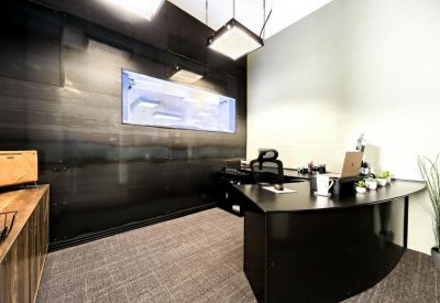 Reception desk area with a dark curved counter and a large wall-mounted monitor.