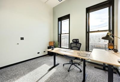 Private office featuring a large window, standing desk, and ergonomic chair.