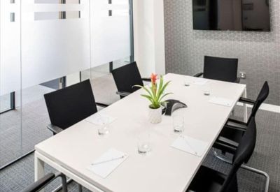 Professional meeting room with a white table, black executive chairs, and frosted glass walls.