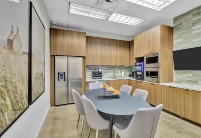 Fully equipped communal kitchen and breakroom with wood cabinetry and dining table.