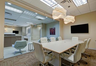 Bright conference room with a white table, modern pendant lights, and glass walls.