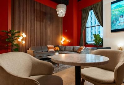 Intimate lounge area with a wood-paneled accent wall, grey sectional sofa, and round cafe table.