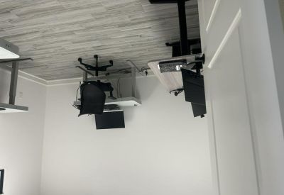 Shared workspace with multiple desks, cabinets, and a tall tower fan.