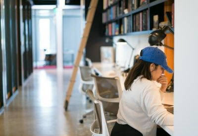 Private workstation area with white desks and a blue baseball cap on a worker.