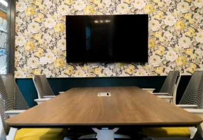 Modern conference room with a floral wallpaper feature wall and a long wooden table.