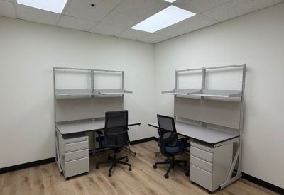 Private office featuring two modern grey workstations with overhead shelving.