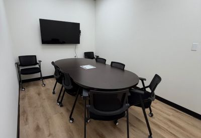 Meeting room featuring a long rectangular wood table, whiteboard, and television.
