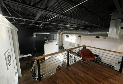 Industrial loft workspace with exposed ductwork and a wooden mezzanine.