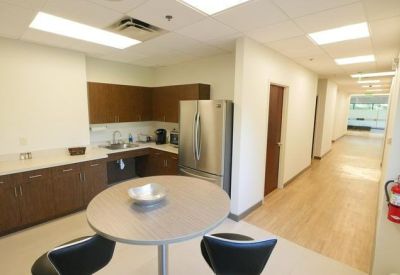 Modern office breakroom and kitchen area with a small dining table.