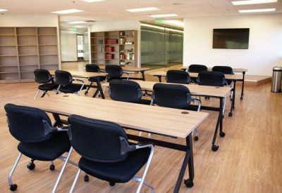 Training or seminar room with multiple rows of tables and black chairs.