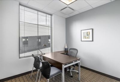 Private office with a large window, wooden desk, and two guest chairs.