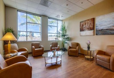 Spacious waiting lounge with leather armchairs and a glass coffee table.