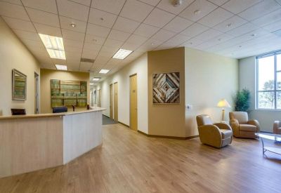 Bright reception area with wood flooring and a curved wooden front desk.