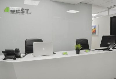 Reception area with a white desk and plants.