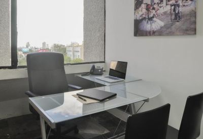 Private office with glass desk and city view.