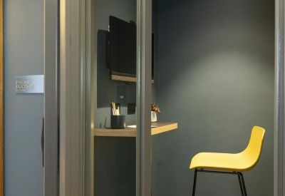 Private phone booth or study nook with a yellow chair and grey acoustic walls.