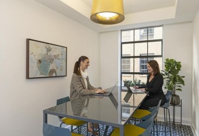 Bright coworking space with two people working at a sleek high-top table.