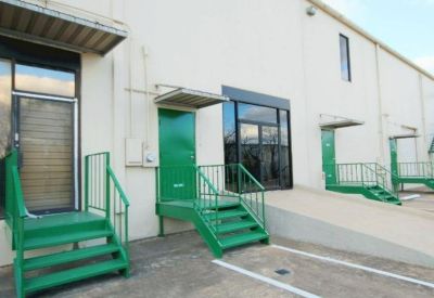 Industrial rear building access with green metal staircases and loading bay doors.