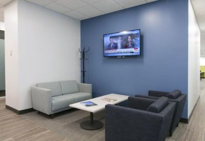 Lounge area with a blue accent wall, wall-mounted TV, and grey seating.