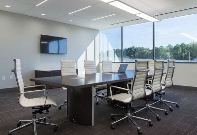 Bright boardroom with a dark wood table and large windows overlooking trees.
