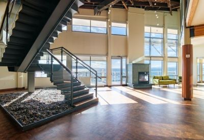 Spacious lobby featuring a grand staircase, stone floor, and large windows overlooking the bay.