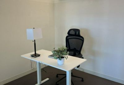 Bright private office with white standing desk, ergonomic chair, and table lamp.