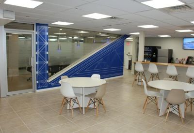 Spacious communal lounge and break area with round white tables, cafe seating, and blue accent walls.