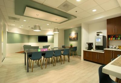 Spacious communal breakroom with dining tables and a modern coffee station.