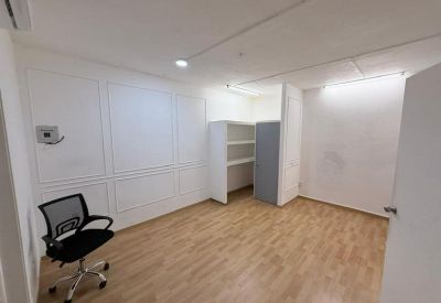 Bright workspace with wood-look flooring, white paneled walls, and a black mesh chair.