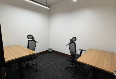 Private two-person office with light wood desks and ergonomic chairs.