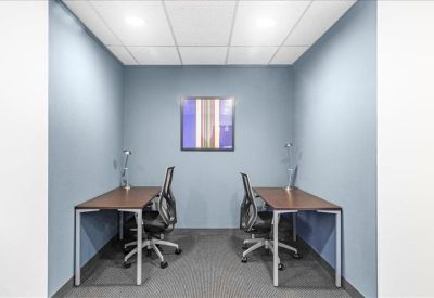 Symmetrical two-person internal office suite with blue walls and matching desks.