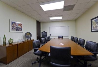 Conference room featuring a long wooden table, whiteboard, and a wooden sideboard with decor.