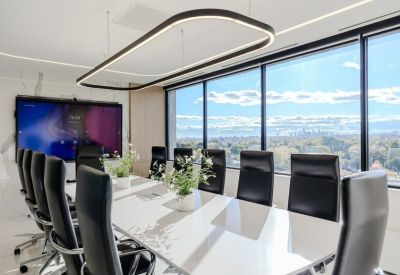 Large boardroom with a long white table, black leather chairs, and expansive window views.