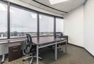 Bright corner office with two desks and large windows overlooking the city.