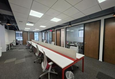 Spacious open-plan workspace with rows of white desks and red accents.