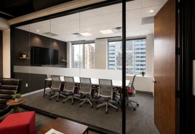 Glass-walled boardroom featuring a large white table and city views.