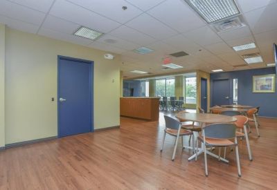 Communal break area with small round tables, grey chairs, and a blue accent wall.