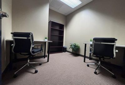 Private two-person office suite with black leather chairs and a dark wood bookshelf.