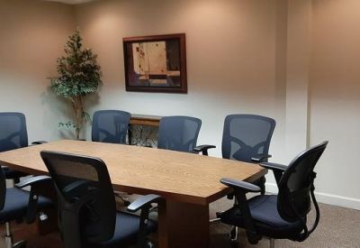 Meeting room with a wooden table, ergonomic mesh chairs, and a small indoor plant.
