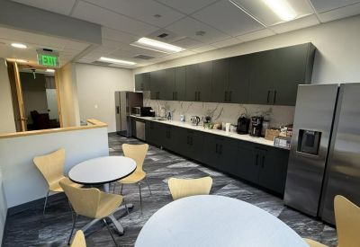 Communal kitchen and break area with dark cabinetry, stainless steel appliances, and cafe seating.