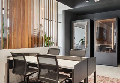 Modern coworking space with white desks, ergonomic black chairs, and a decorative wood slat partition.