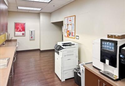 Office breakroom and copy area with coffee machine and wood-look flooring.