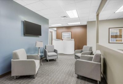 Waiting area with grey armchairs, a blue feature wall, and a television.